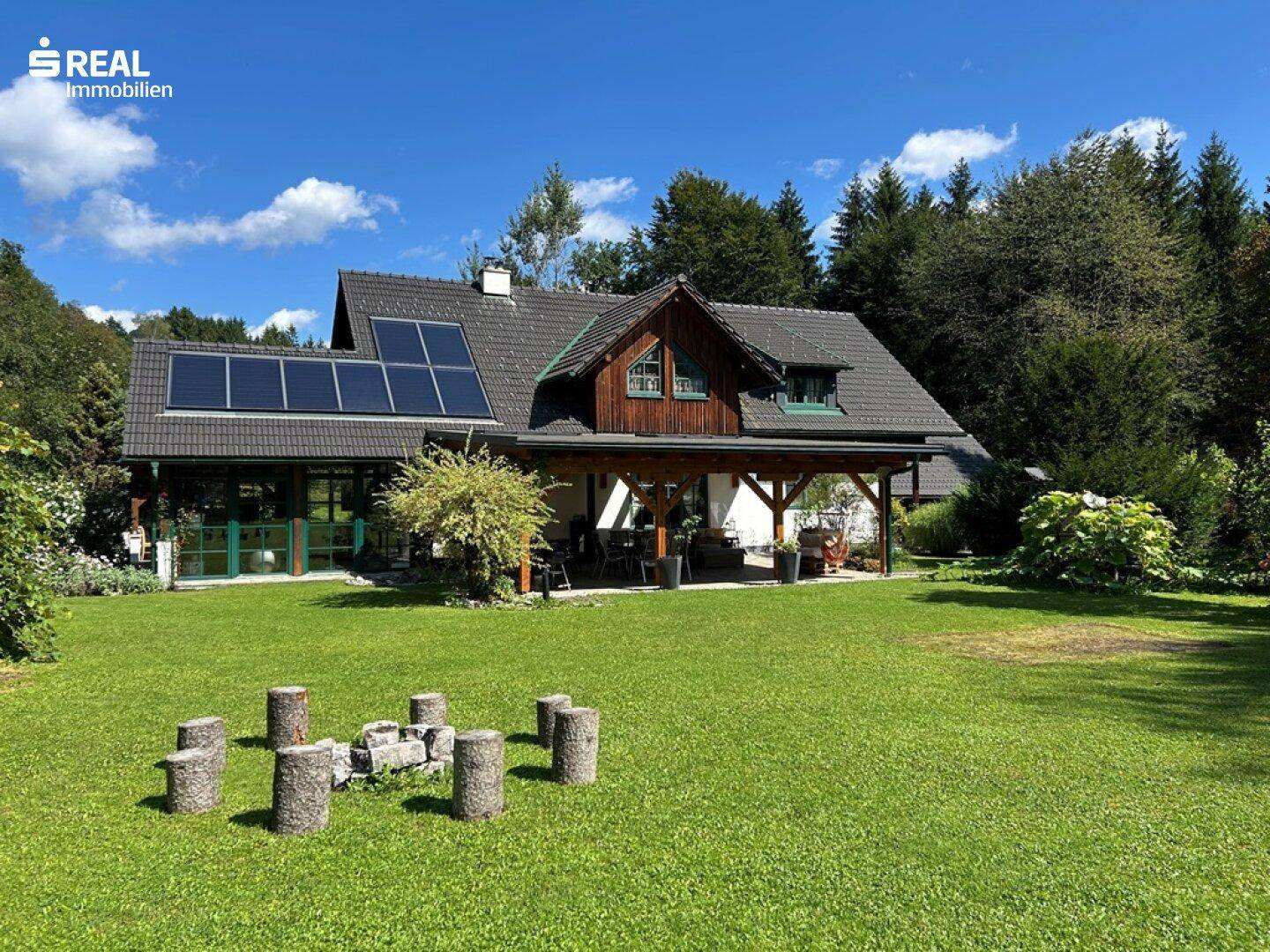 Weitläufiger Garten mit Rasenfläche und gemütlicher Feuerstelle, umgeben von Natur.