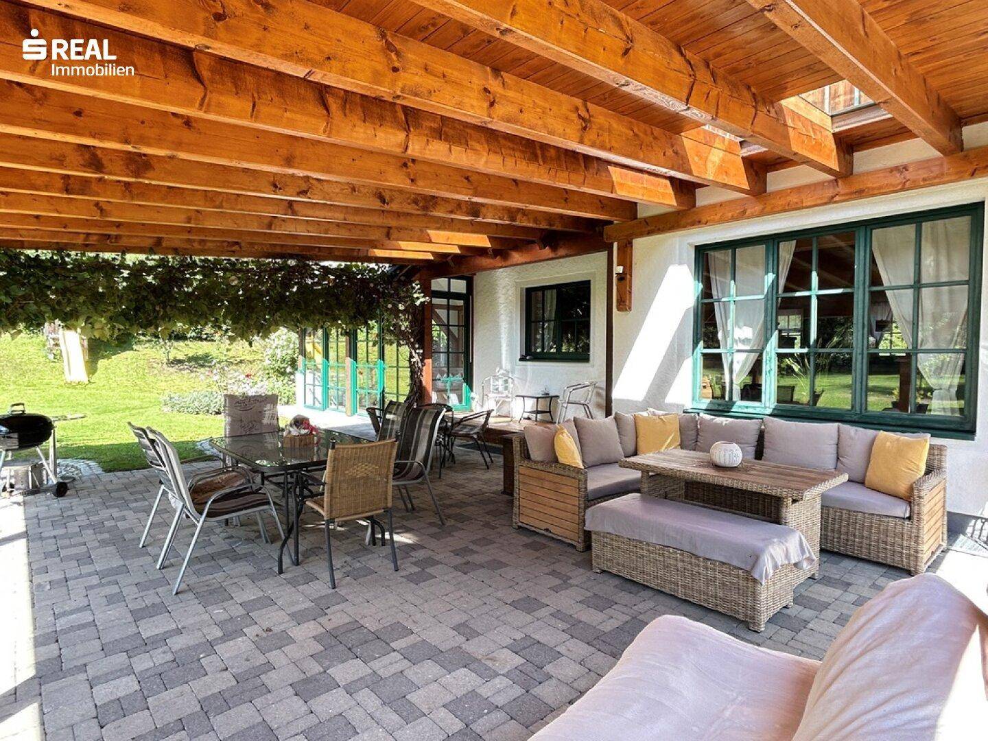 Geräumige, überdachte Terrasse mit bequemen Lounge-Möbeln und Essbereich, ideal für gesellige Stunden.