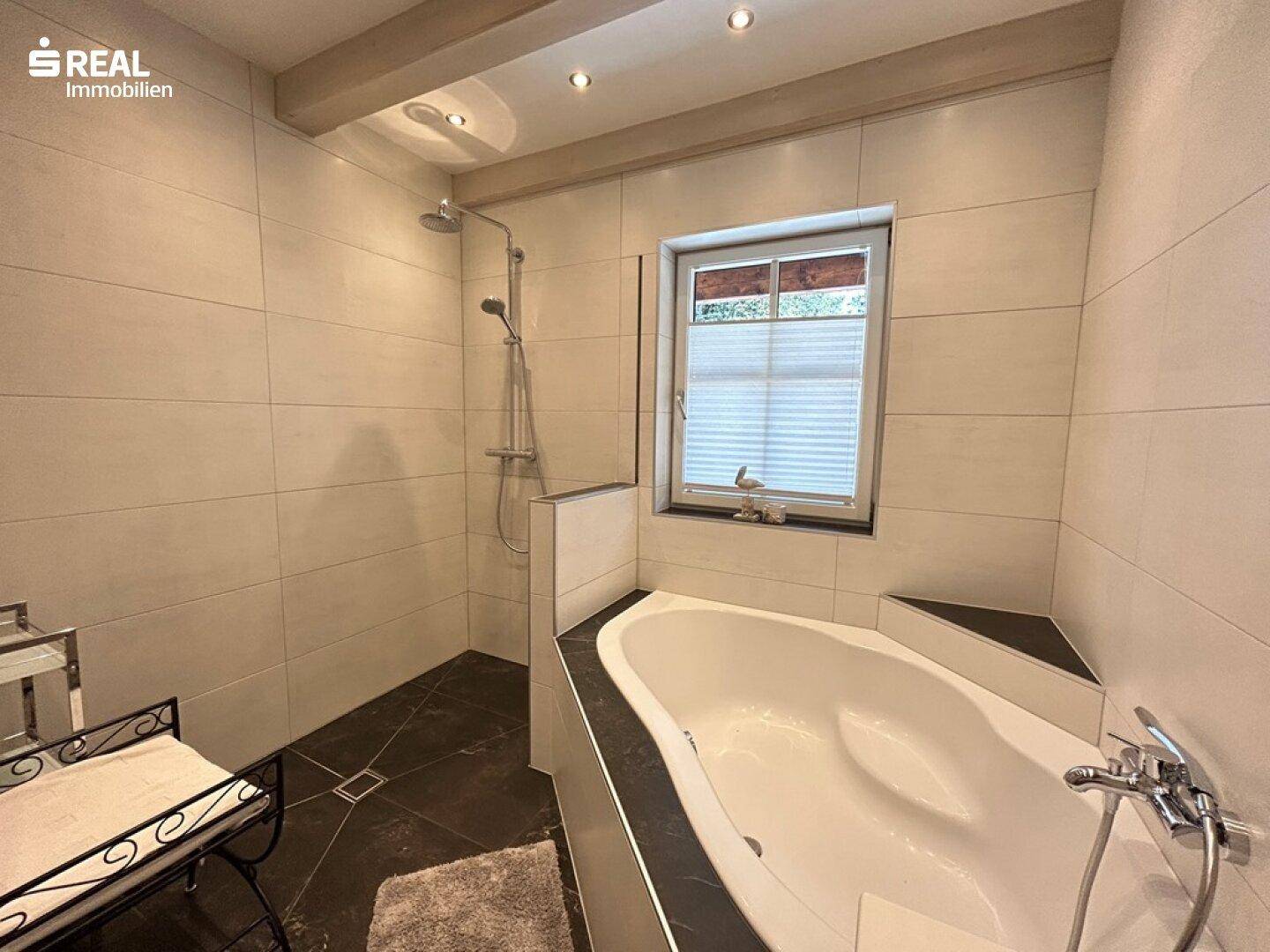 Modernes Badezimmer mit Eckbadewanne, Dusche und hellen Fliesen.