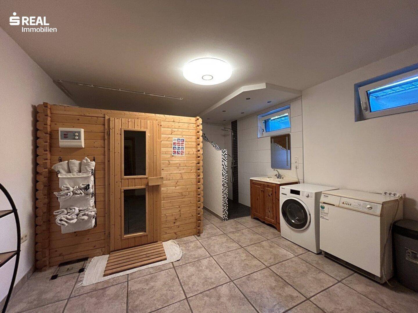 Hauswirtschaftsraum mit Waschmaschine, Trockner und integrierter Sauna.