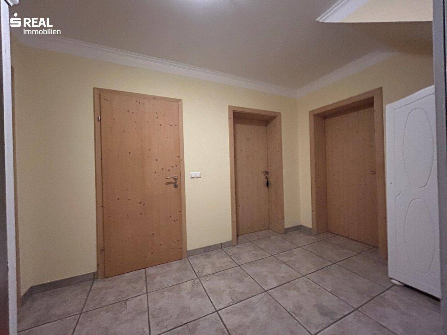 Flur mit Holztüren, Fliesenboden und schlichter Wandgestaltung.
