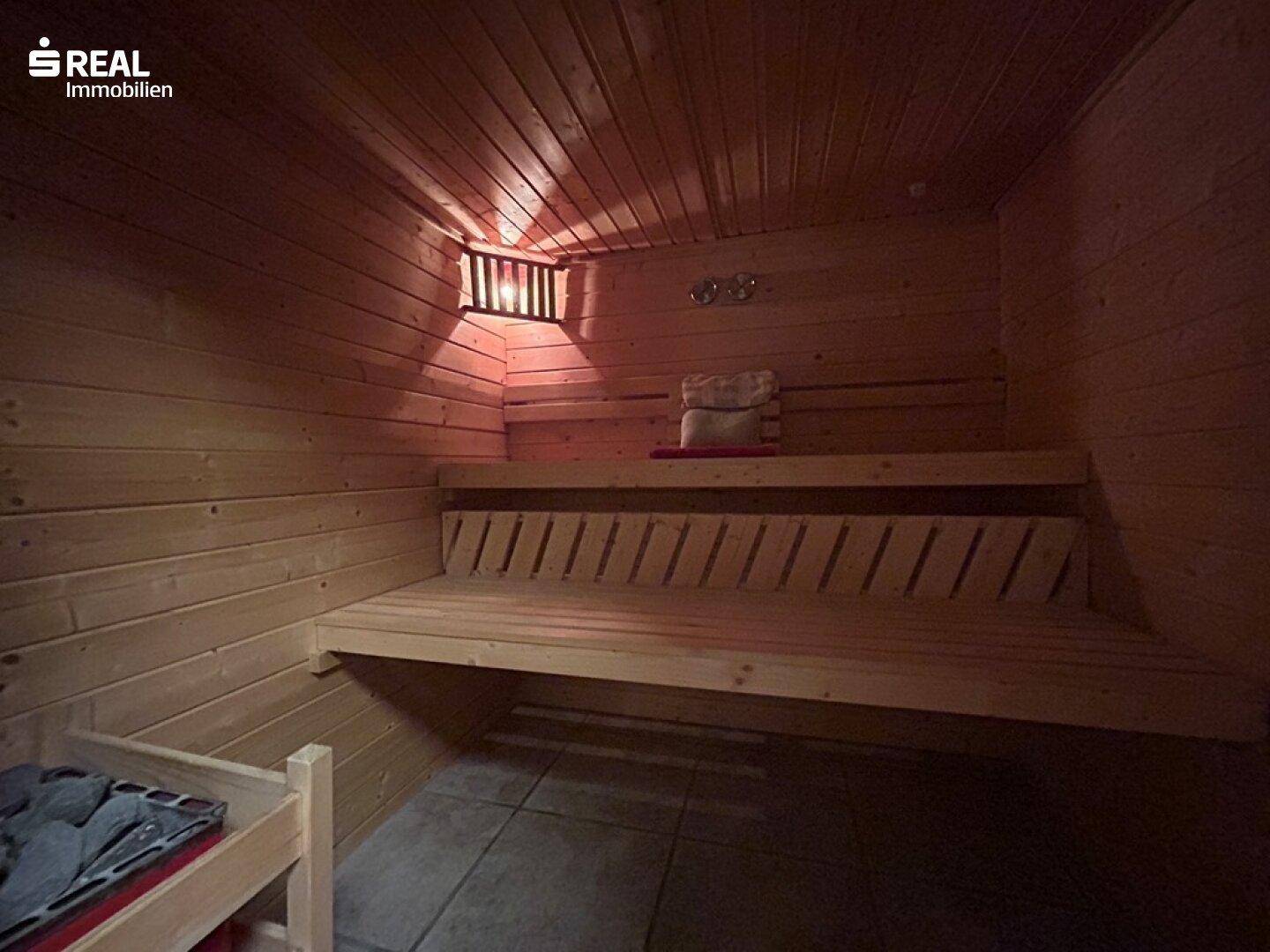 Innenansicht der Holzsauna mit Bänken und stimmungsvoller Beleuchtung.