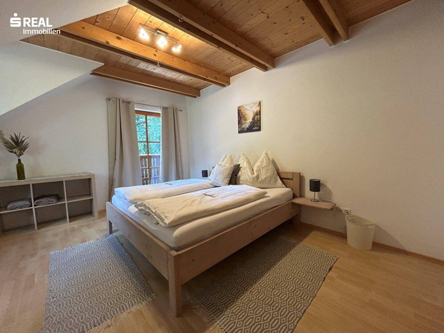 Gemütliches Schlafzimmer im Dachgeschoss mit Holzbalkendecke und Holzboden.