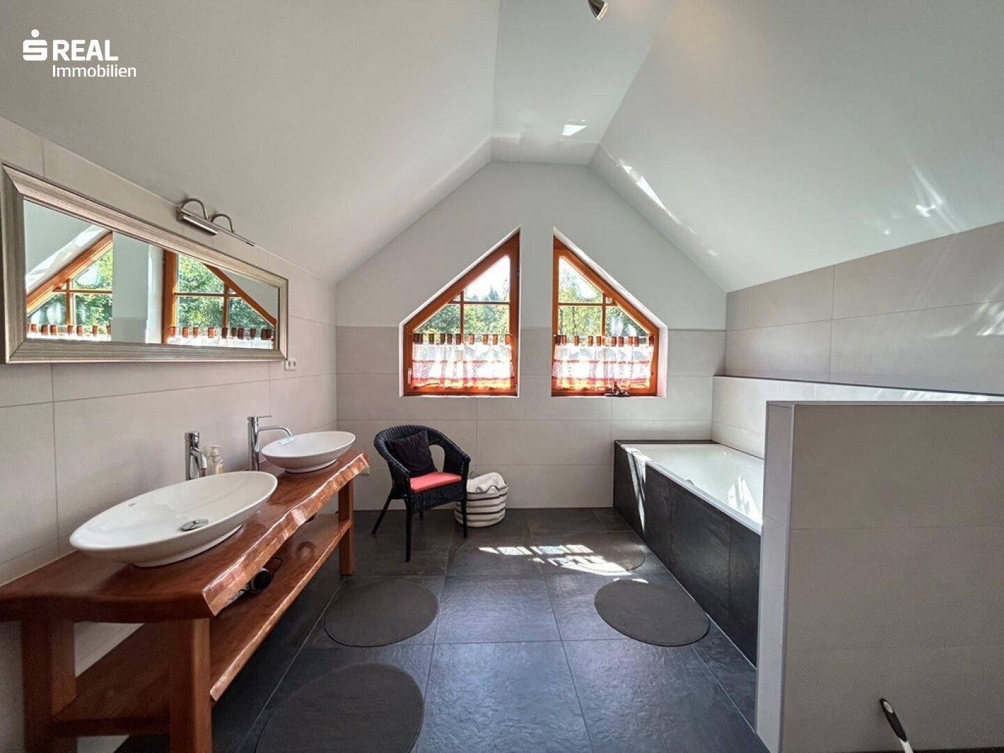 Modernes Badezimmer im Dachgeschoss mit Doppelwaschbecken und Badewanne.