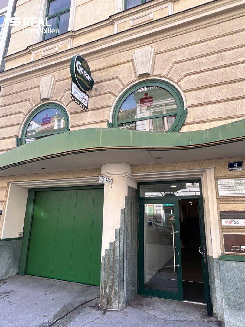 Eingangsbereich eines historischen Gebäudes mit grüner Tür und runden Fenstern.