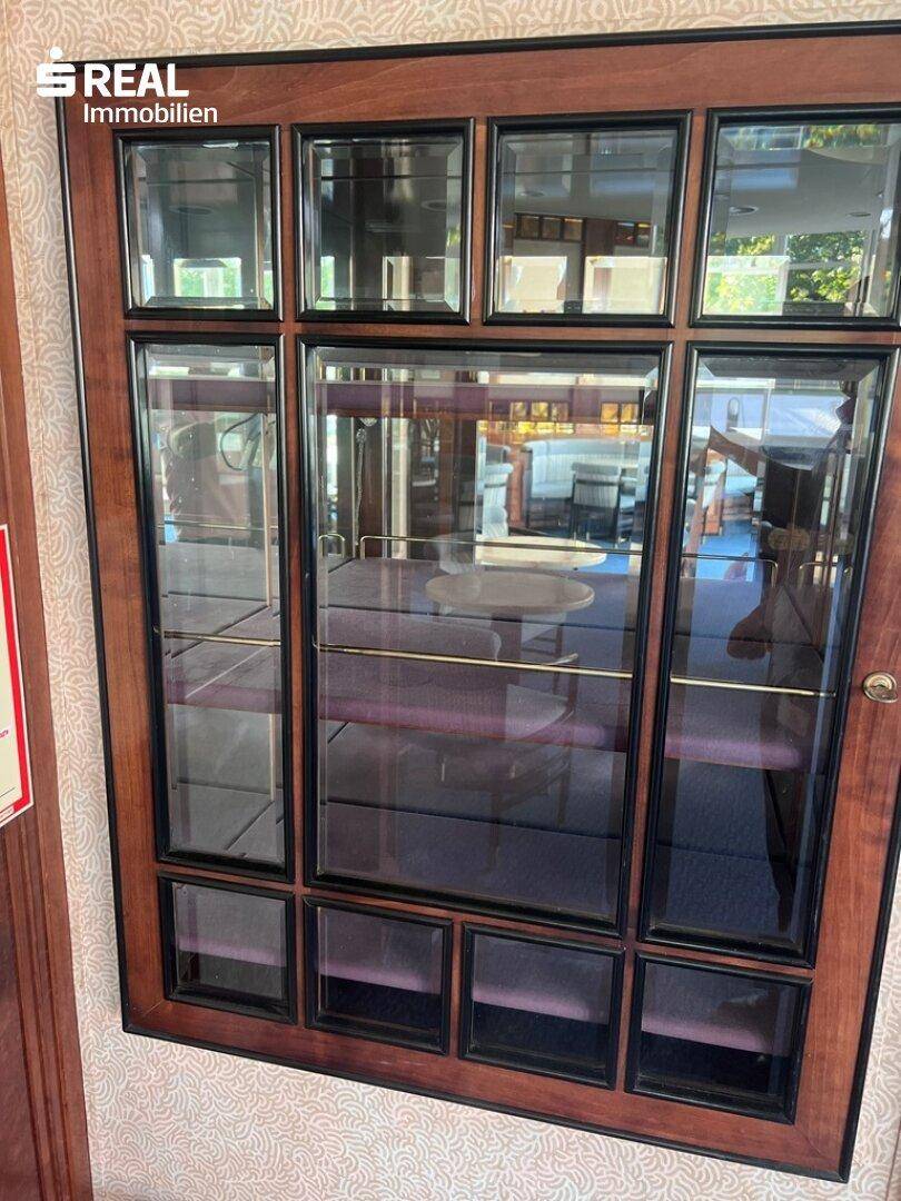 Eine Vitrine mit Glasfächern und Holzrahmen, die den Raum widerspiegelt.