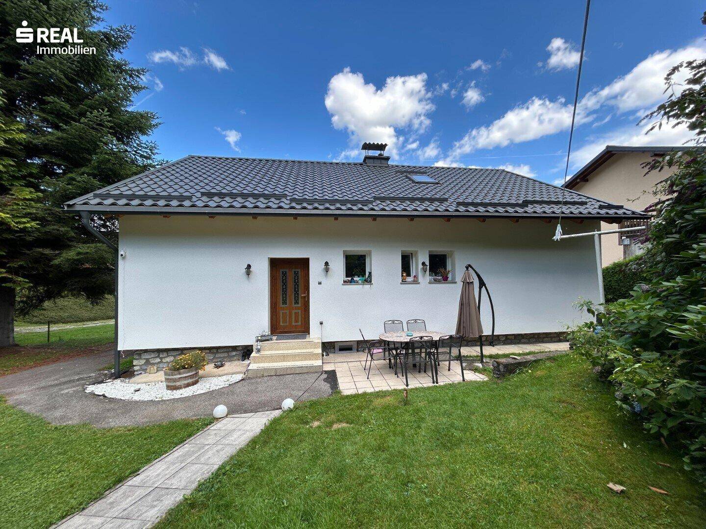Vorderansicht des Einfamilienhauses mit kleiner Terrasse, Garten und gepflegter Grünfläche.
