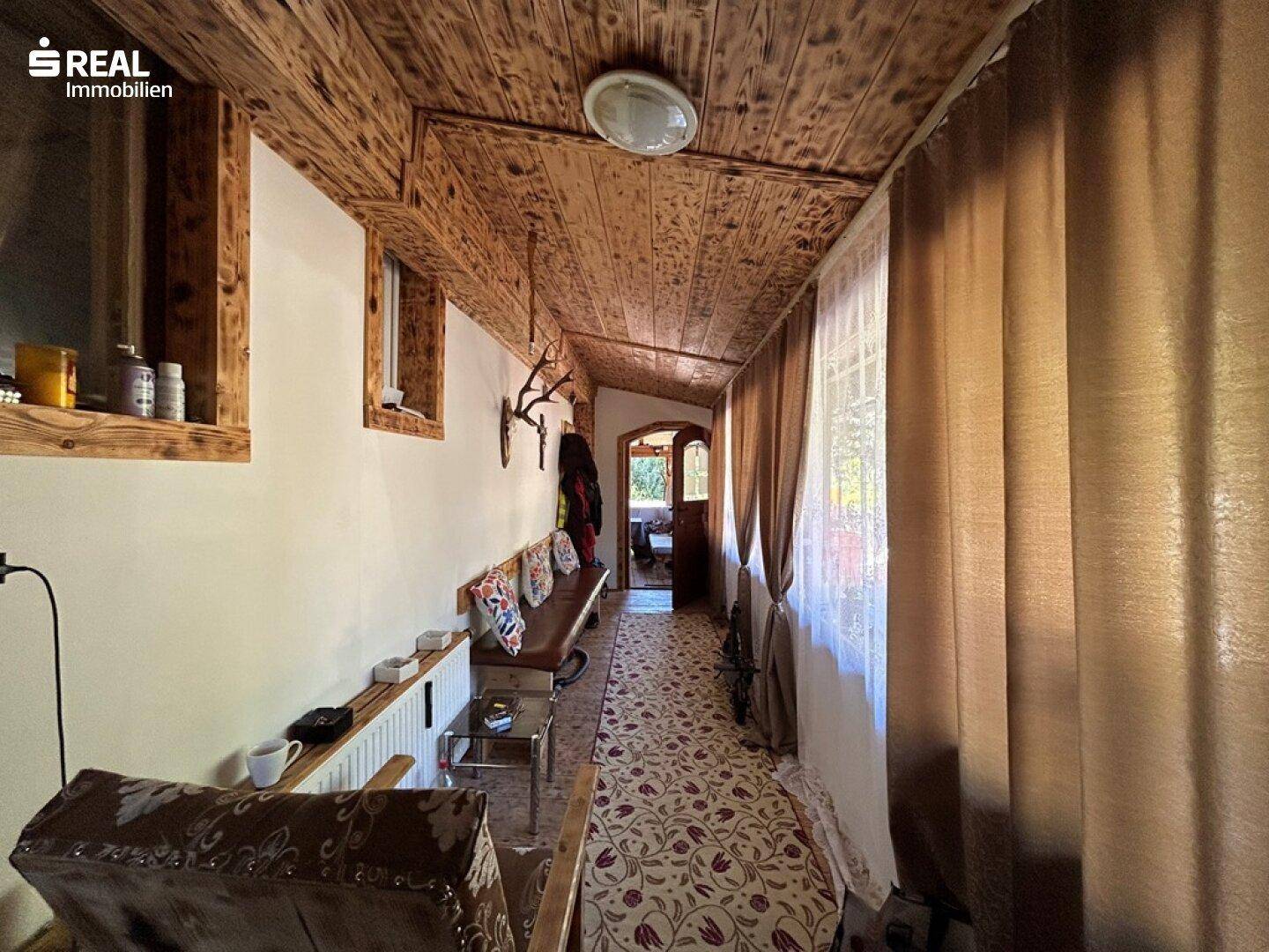 Langer Flur mit Holzdecke, Teppichboden und rustikaler Dekoration.