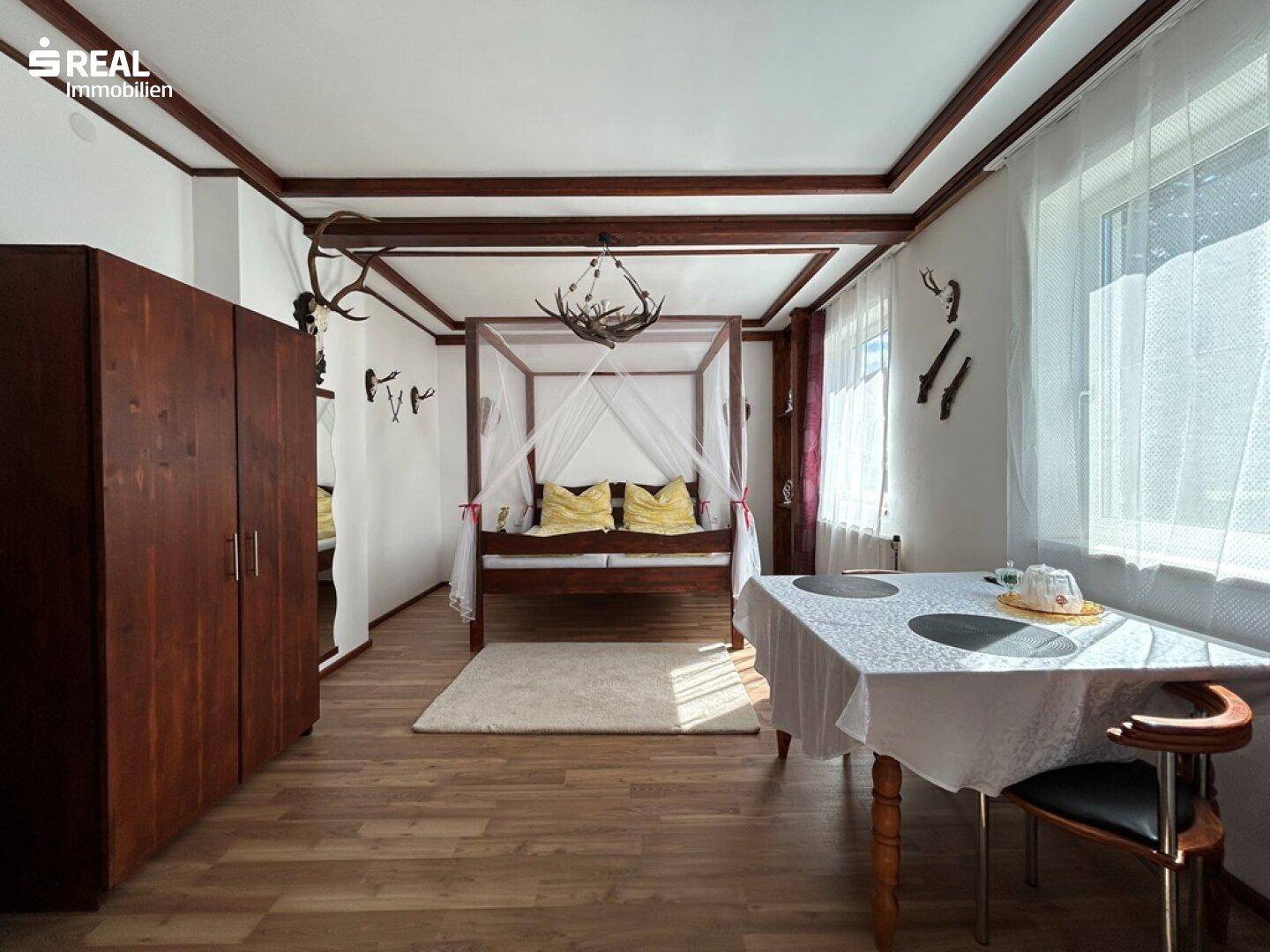 Geräumiges Schlafzimmer mit Himmelbett, Holzboden und rustikalen Akzenten.