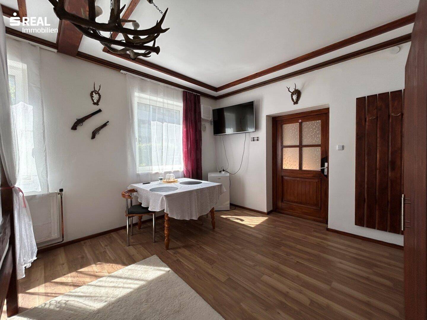 Schlafzimmer mit Holzboden, Fernseher und traditioneller Holztür.