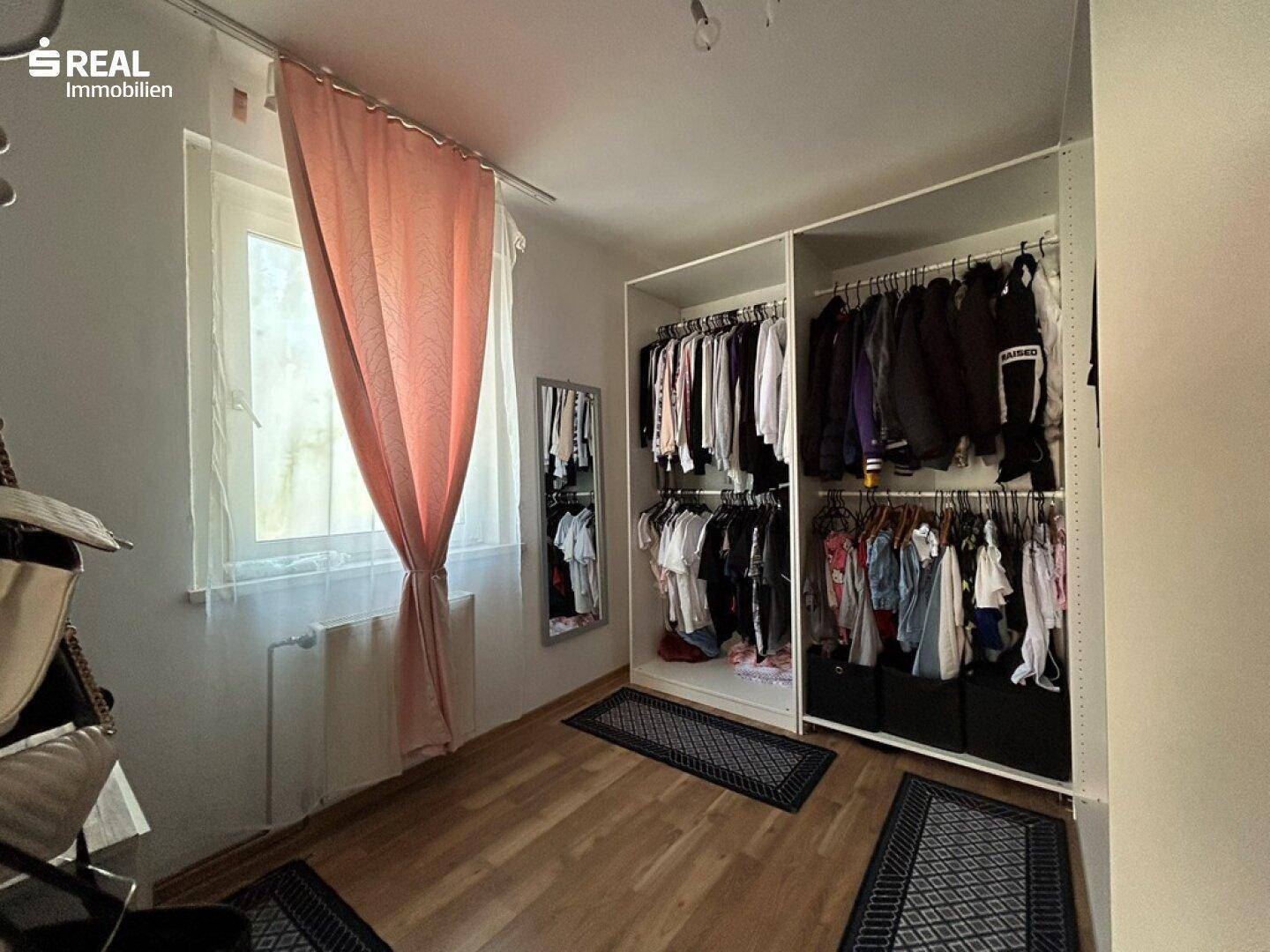 Begehbarer Kleiderschrank im Schlafzimmer mit viel Stauraum und Fenster.