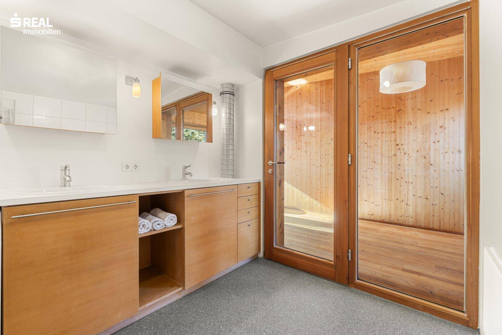 Modernes Badezimmer mit Doppelwaschbecken und integrierter Sauna für Wellnessmomente.