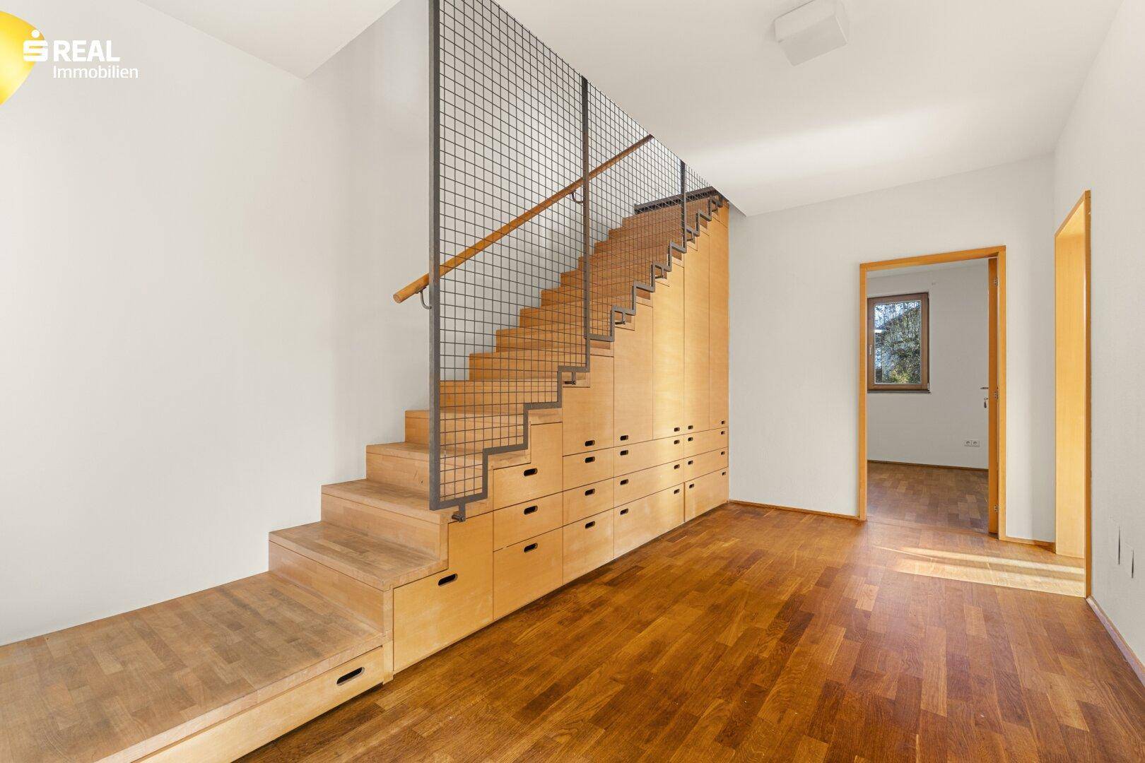Heller Flur mit Holztreppe und integrierten Schubladen für praktischen Stauraum.