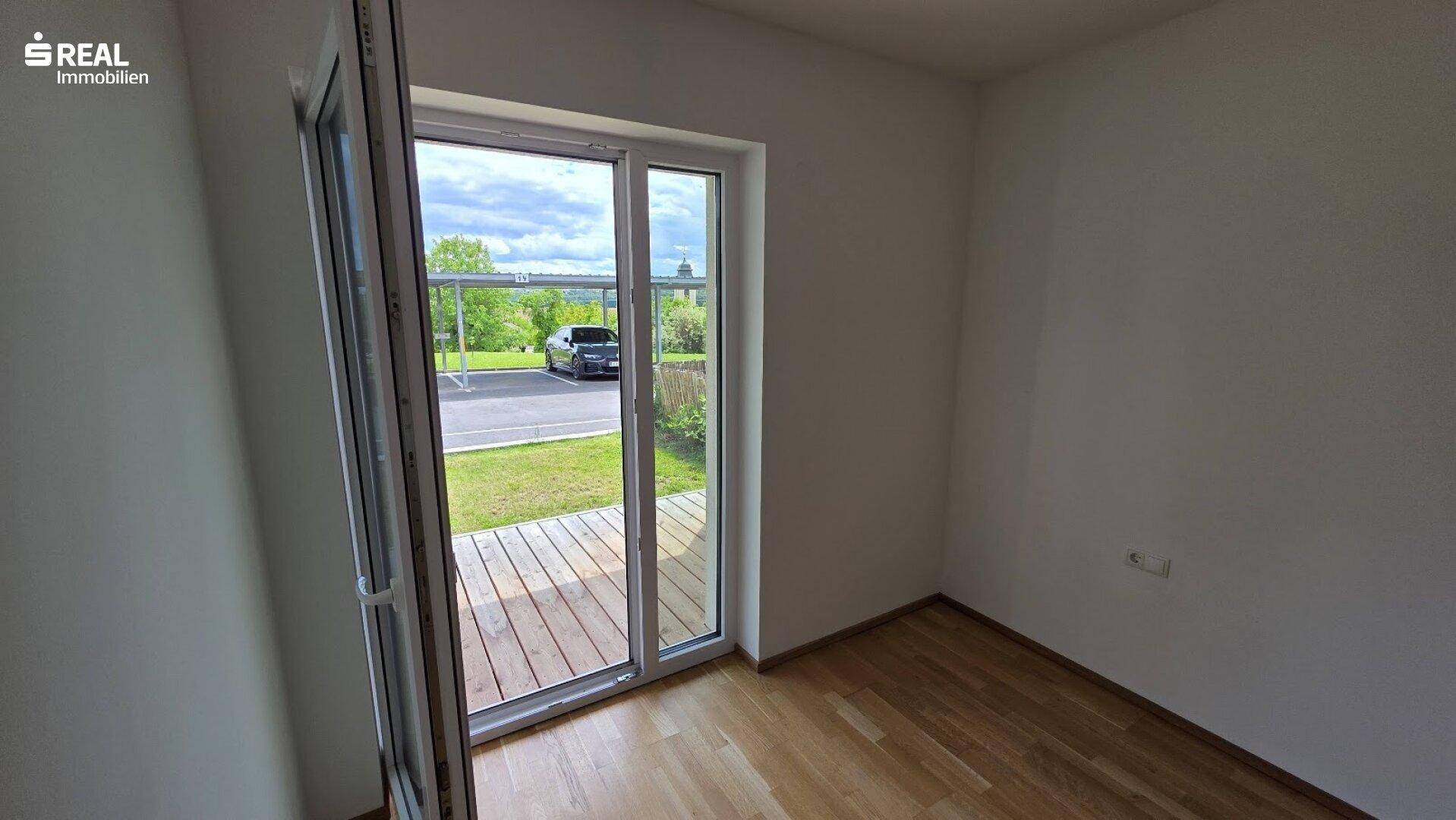 Glastür führt auf eine Holzterrasse, die den Innenraum mit dem Außenbereich verbindet.