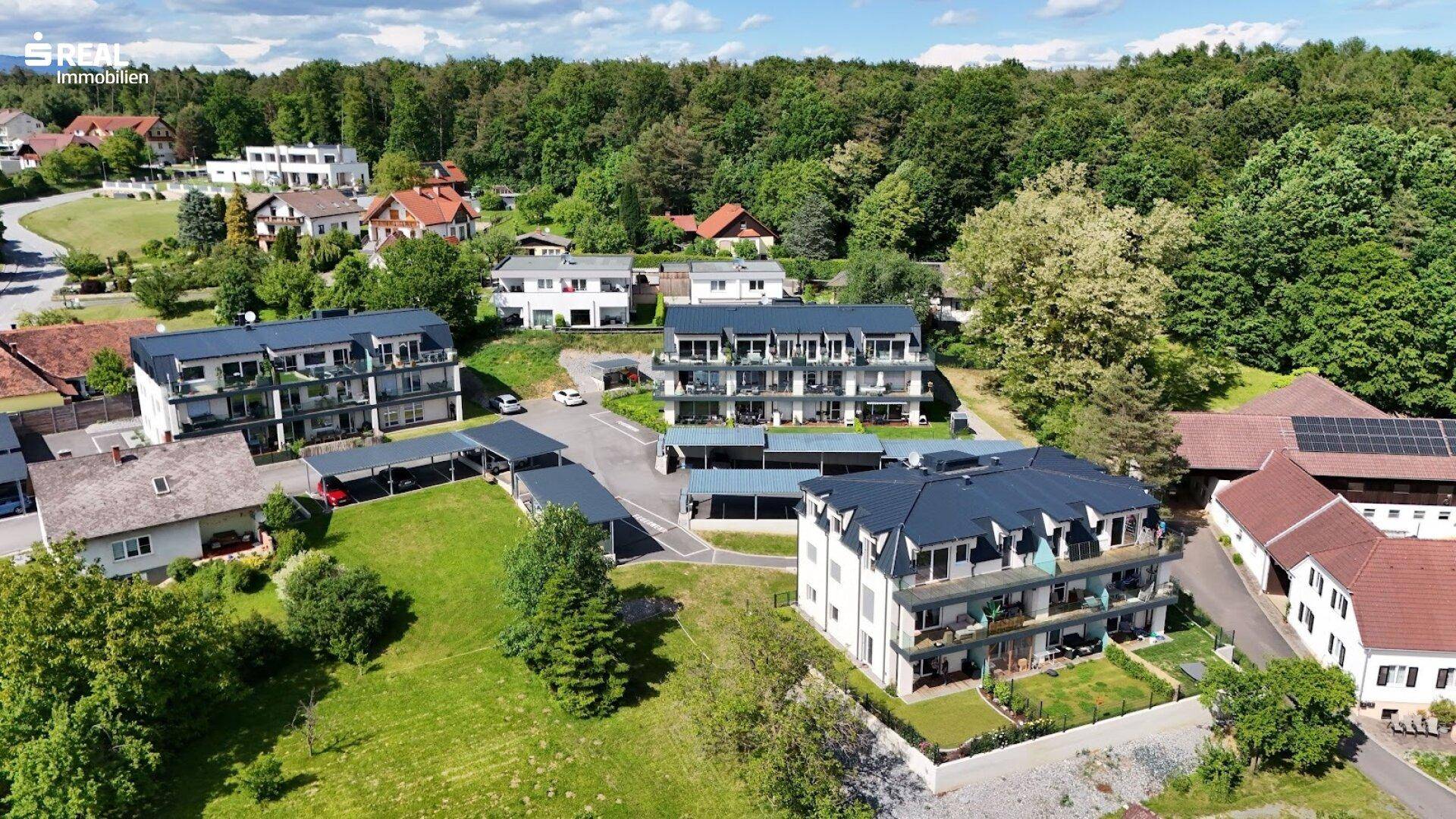 Luftaufnahme einer Wohnsiedlung mit mehreren modernen Gebäuden und viel Grünfläche.