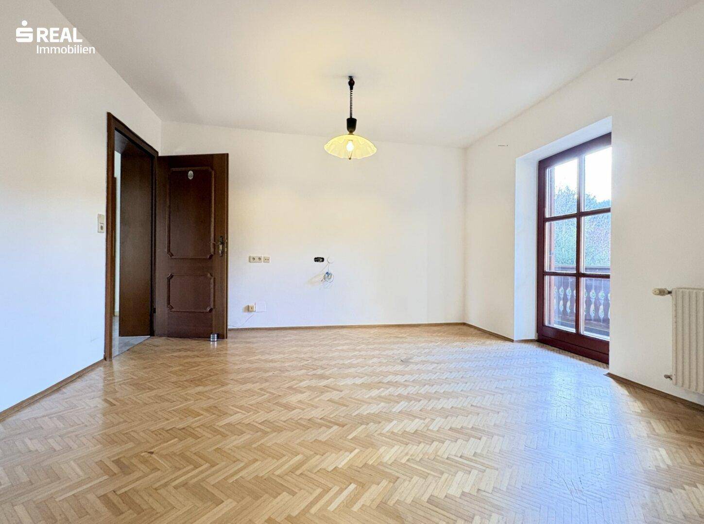 Helles Schlafzimmer mit Fischgrätparkett, Balkonzugang und Holztür.