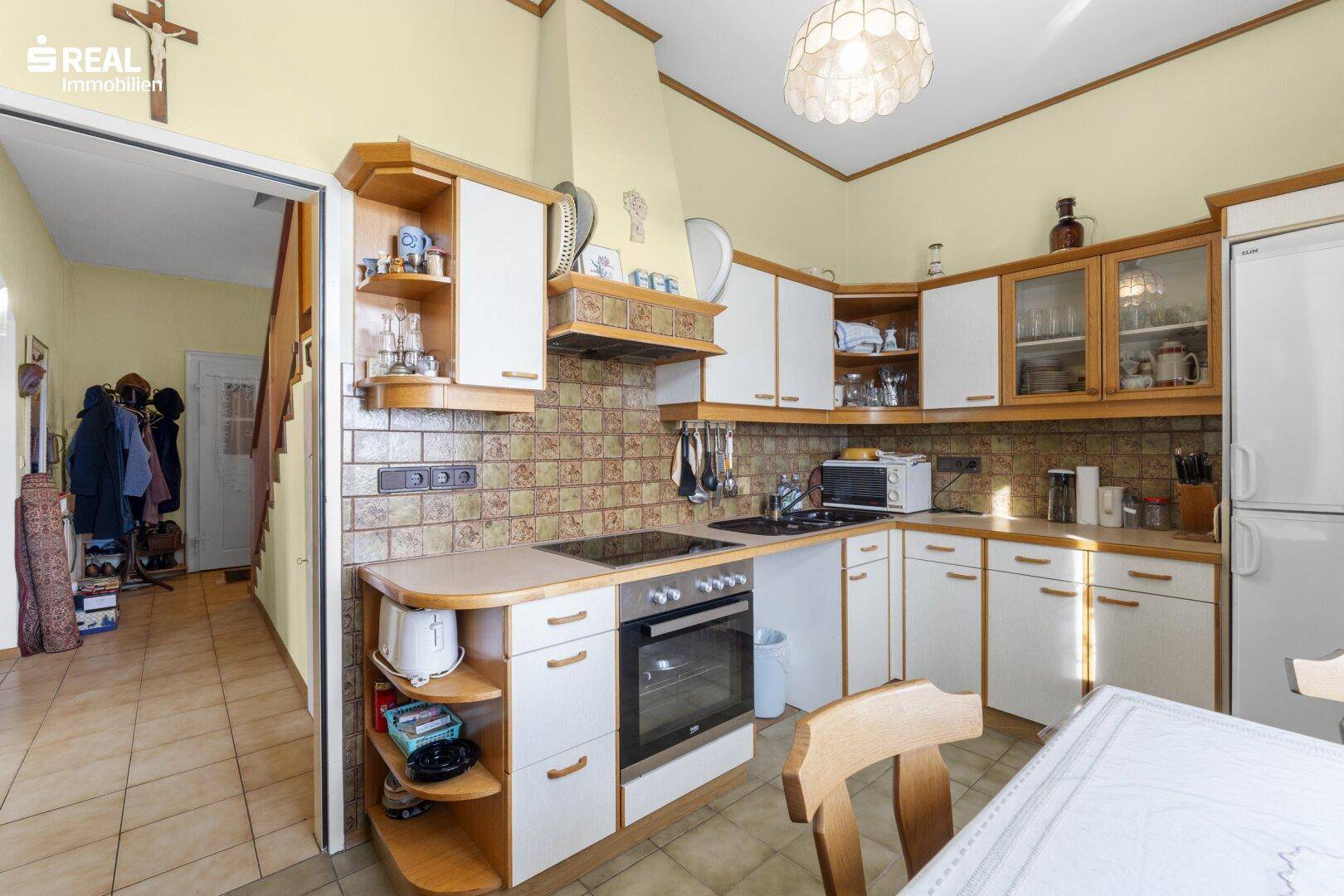 Funktionale Küche mit weißen Schränken, Holzdetails und integrierten Geräten.