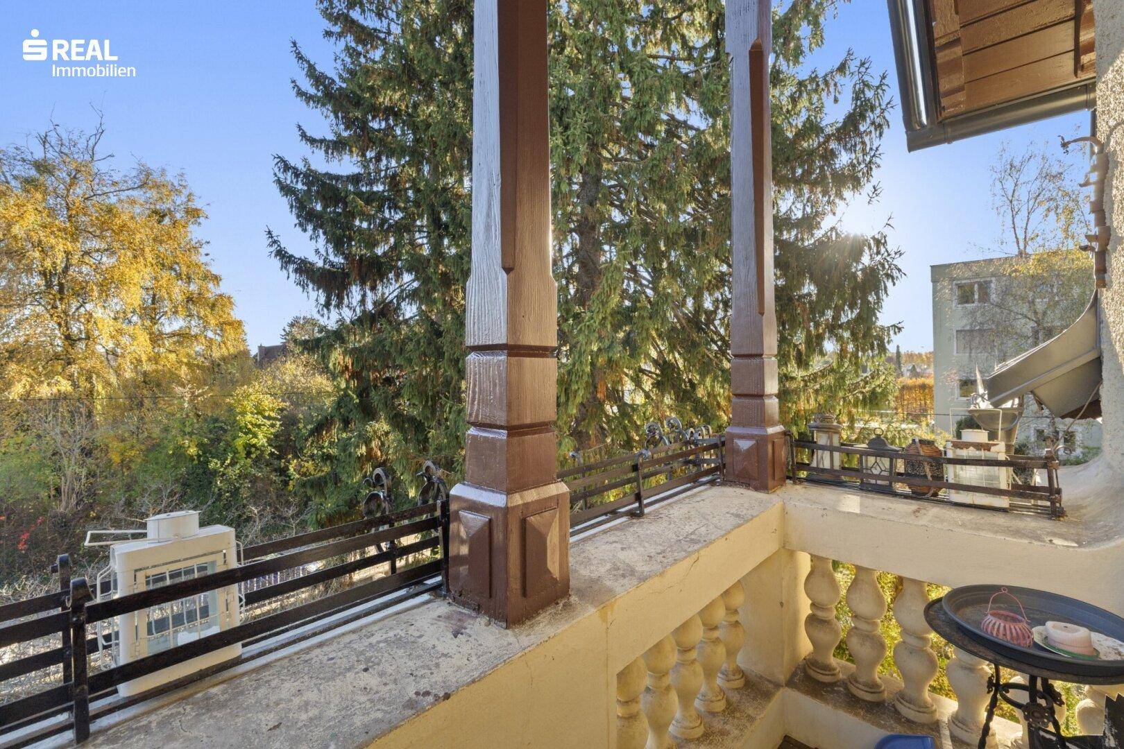 Historischer Balkon mit Holzsäulen und Balustrade, bietet einen schönen Ausblick ins Grüne.