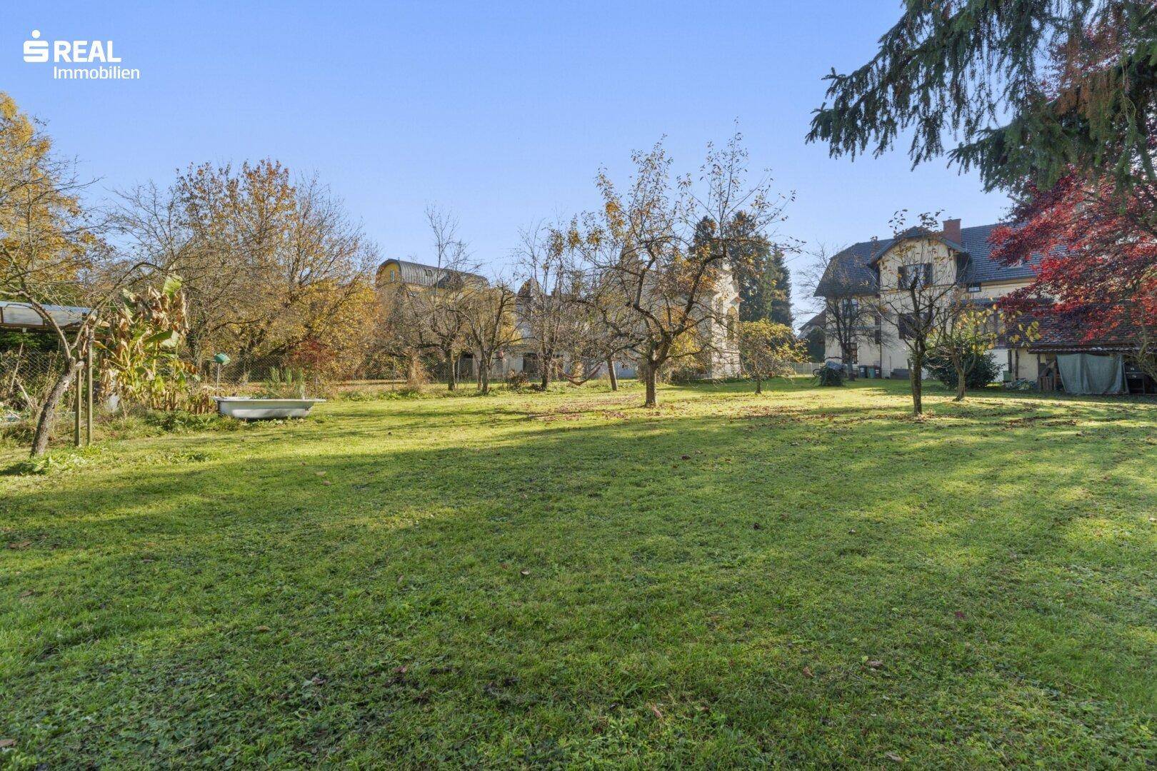 Weitläufige Grünfläche des Gartens mit Obstbäumen und Blick auf die Villa.