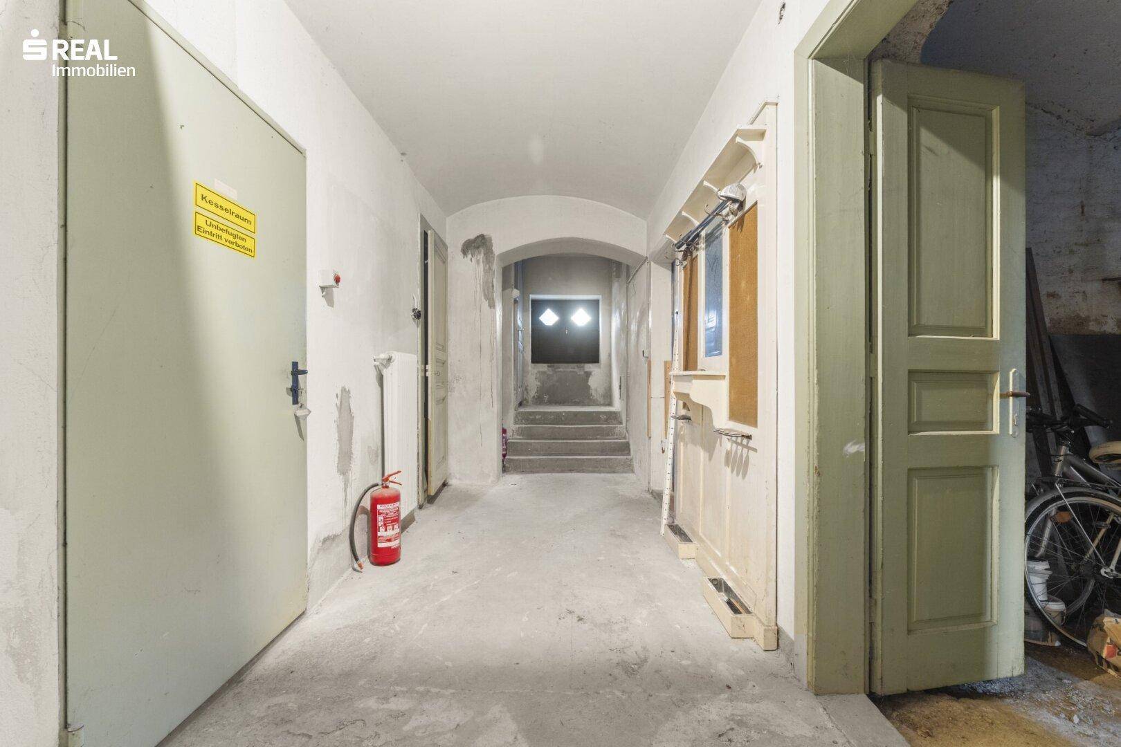 Kellerflur mit Betonboden und Zugang zu verschiedenen Kellerräumen.