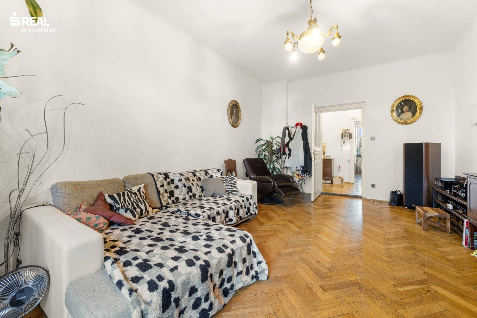 Gemütliches Wohnzimmer mit Parkettboden, großem Sofa und klassischer Dekoration.