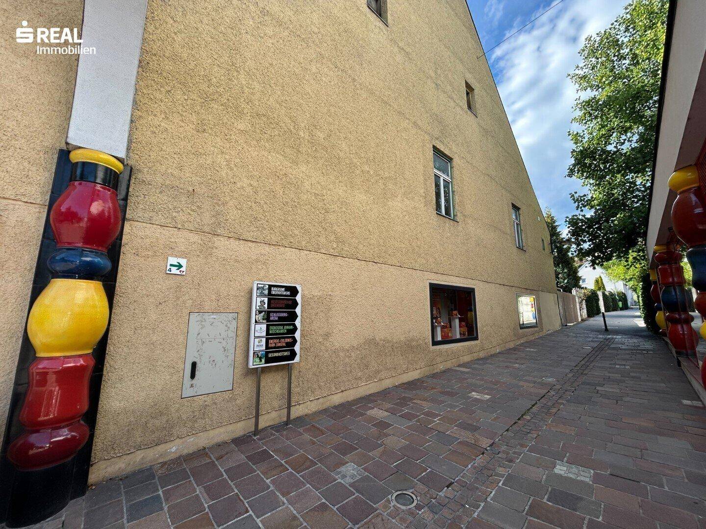 Seitenansicht eines Gebäudes mit schmaler Gasse und dekorativen Elementen an der Fassade.