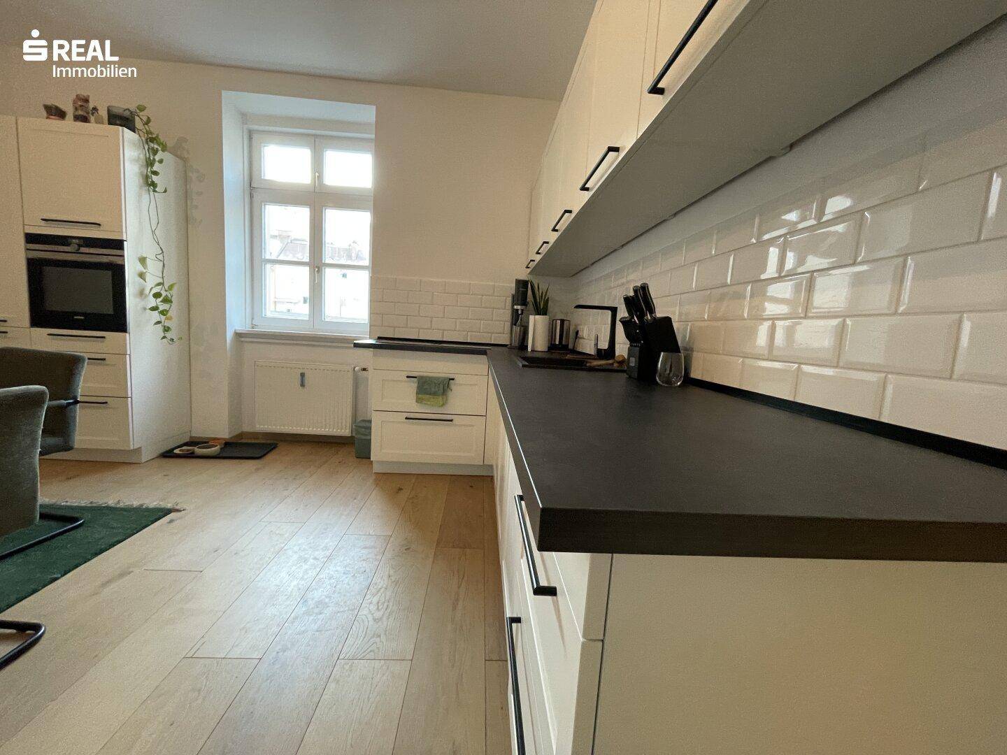 Detailansicht der modernen Küche mit weißem Fliesenspiegel und dunkler Arbeitsplatte.
