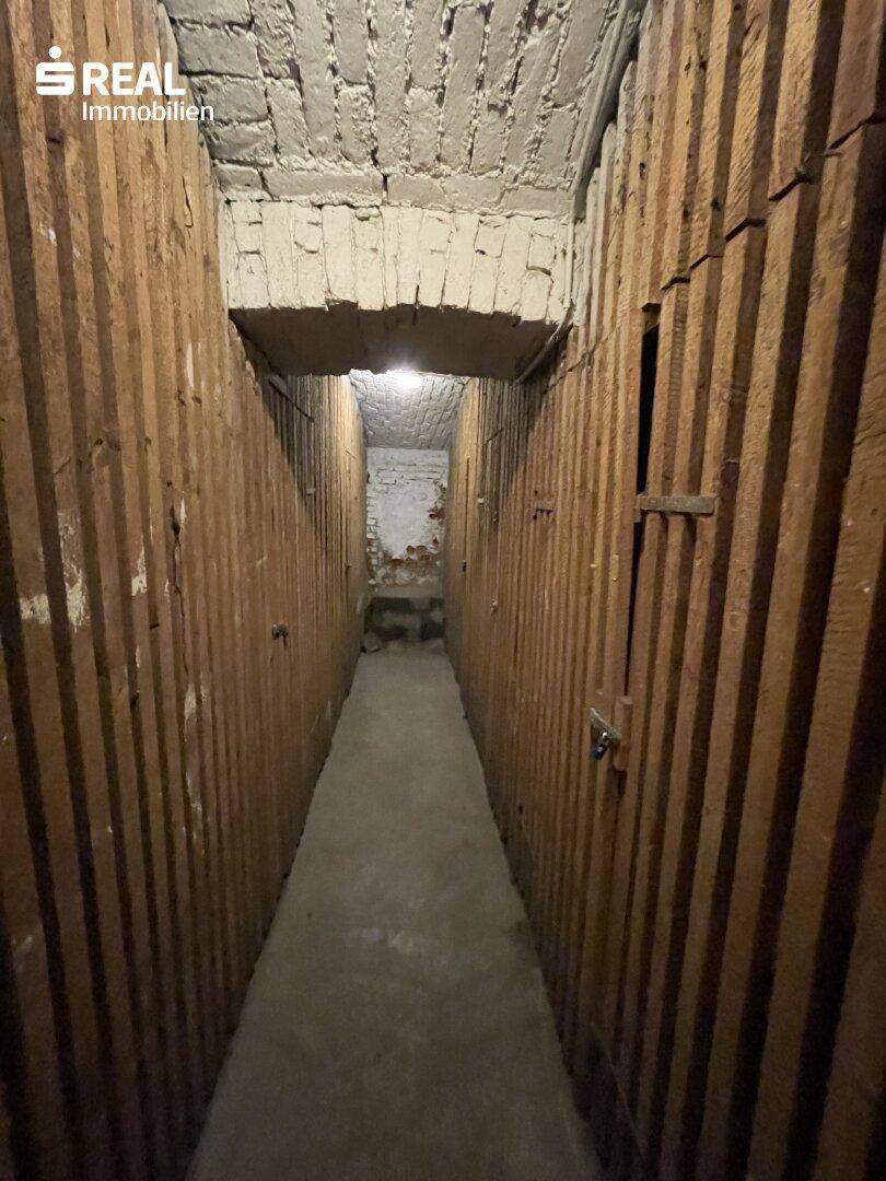 Kellerabteil mit Holzabtrennungen und Betonboden, ideal als Stauraum.