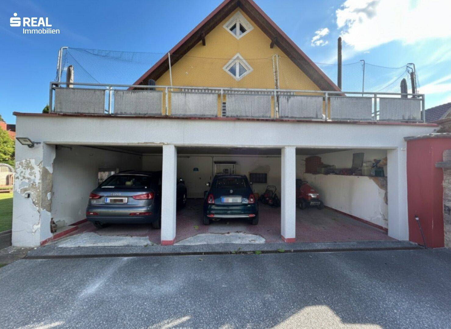 Offene Garage mit drei Stellplätzen und darüberliegender Terrasse, teilweise renovierungsbedürftig.