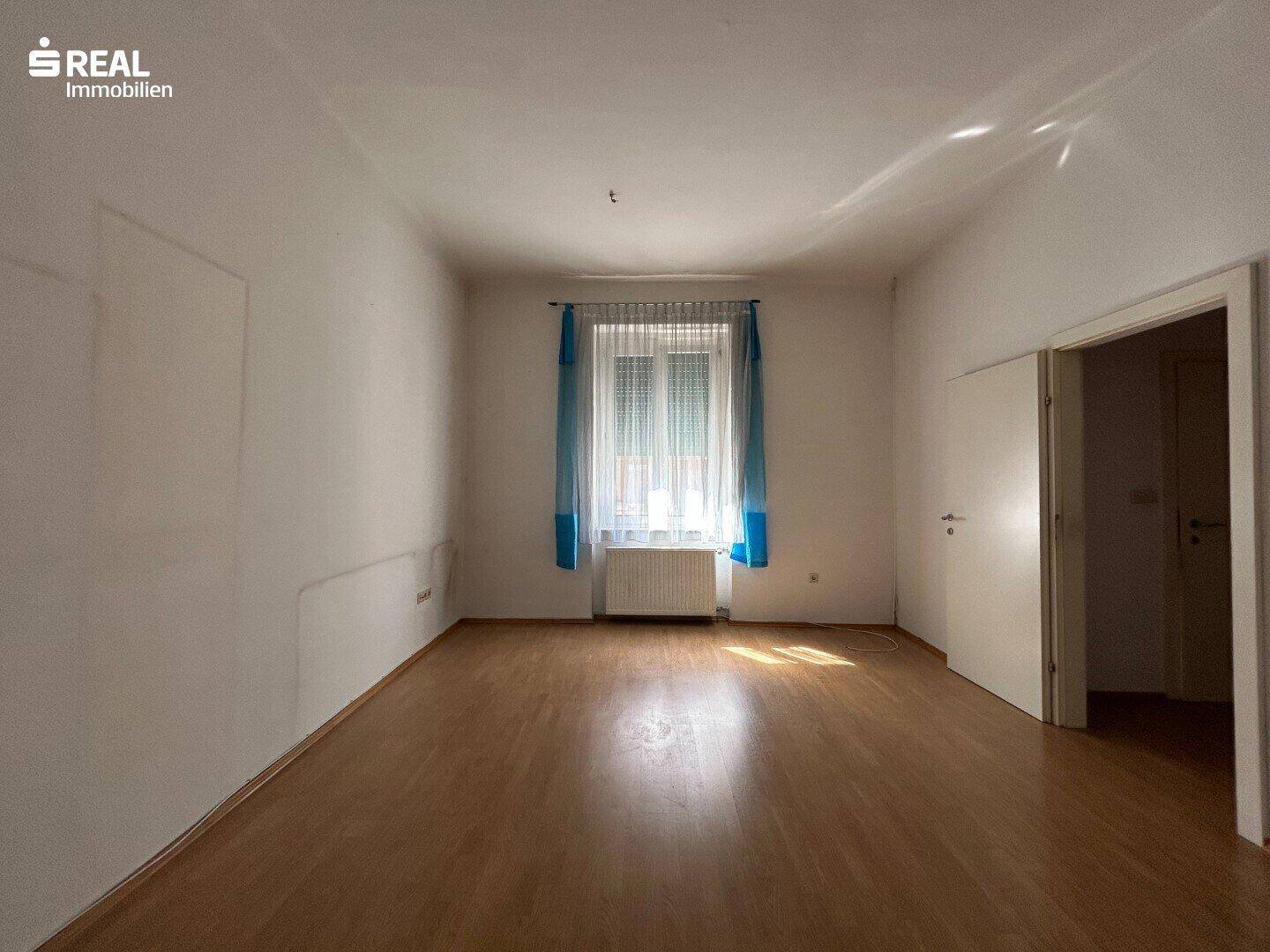 Leerer Raum mit Laminatboden und Fenster, bietet vielseitige Nutzungsmöglichkeiten.