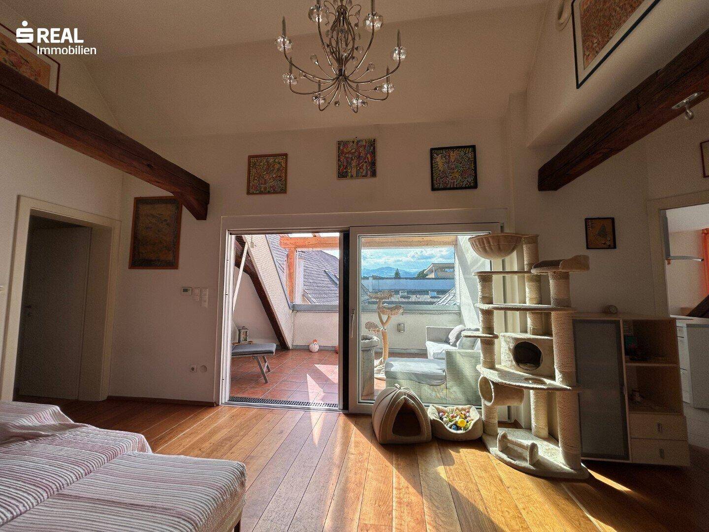 Helles Wohnzimmer mit Holzboden und Zugang zu einer überdachten Terrasse mit Weitblick.