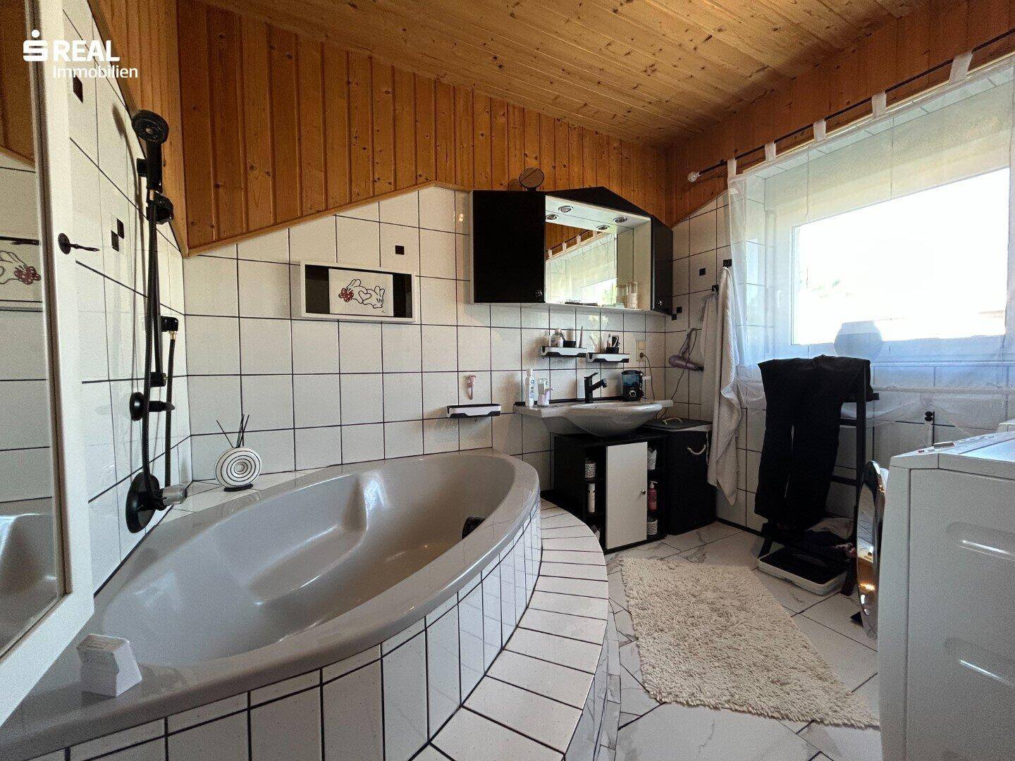 Geräumiges Badezimmer mit Eckbadewanne, Dusche und Waschbecken, hell gefliest und funktional.