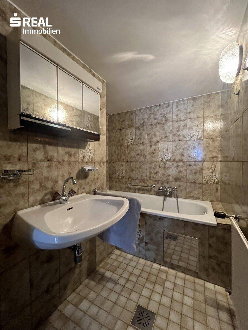 Klassisches Badezimmer mit Badewanne, Waschbecken und Fliesenboden.