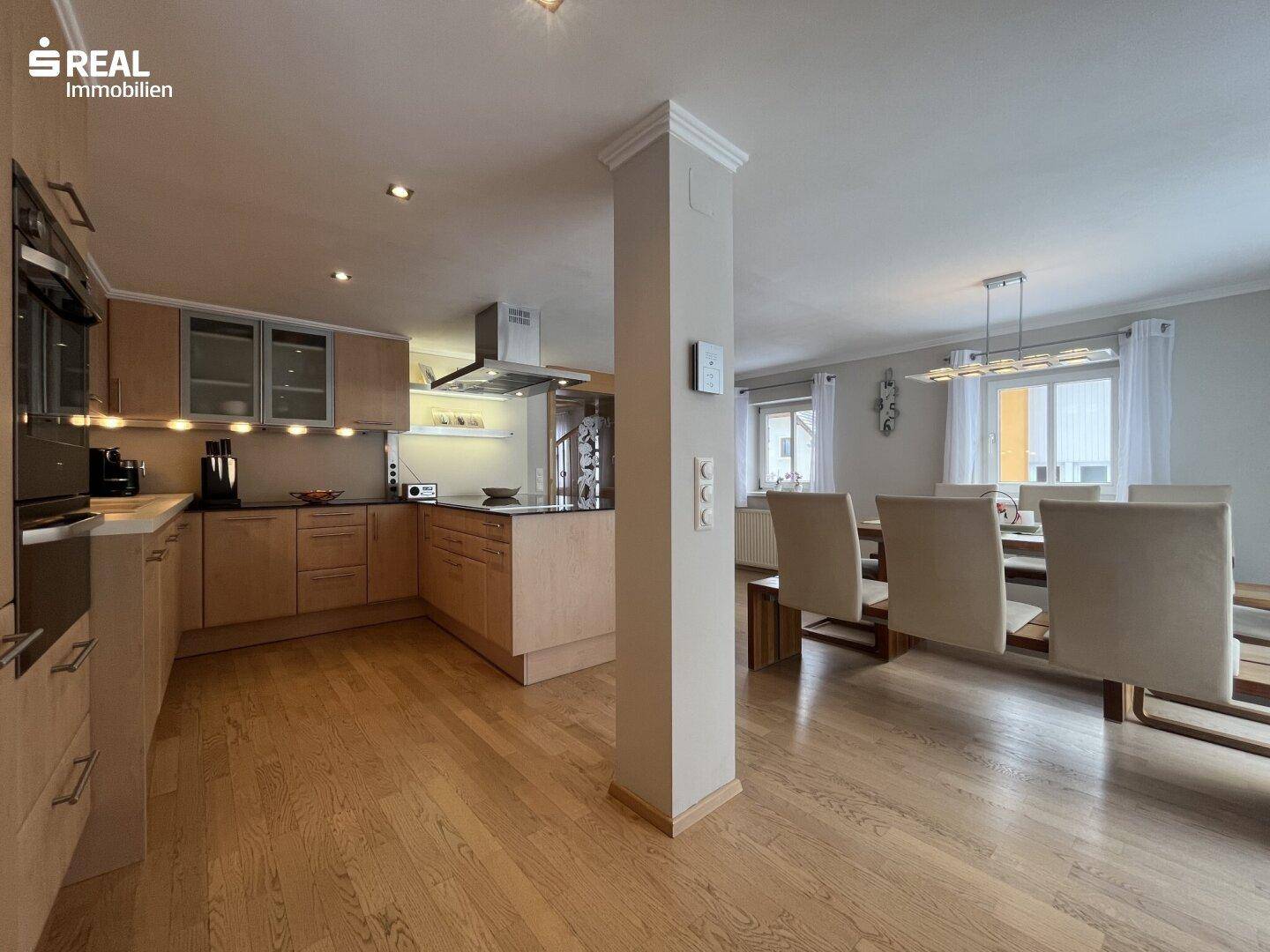 Helle, offene Küche mit Essbereich und Holzboden, ideal für geselliges Beisammensein.