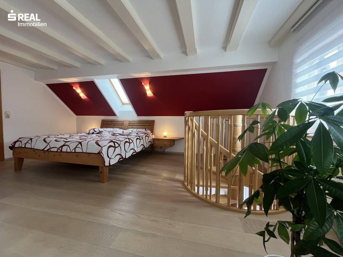 Geräumiges Schlafzimmer im Dachgeschoss mit Holzbalken, Dachfenster und Holzboden.