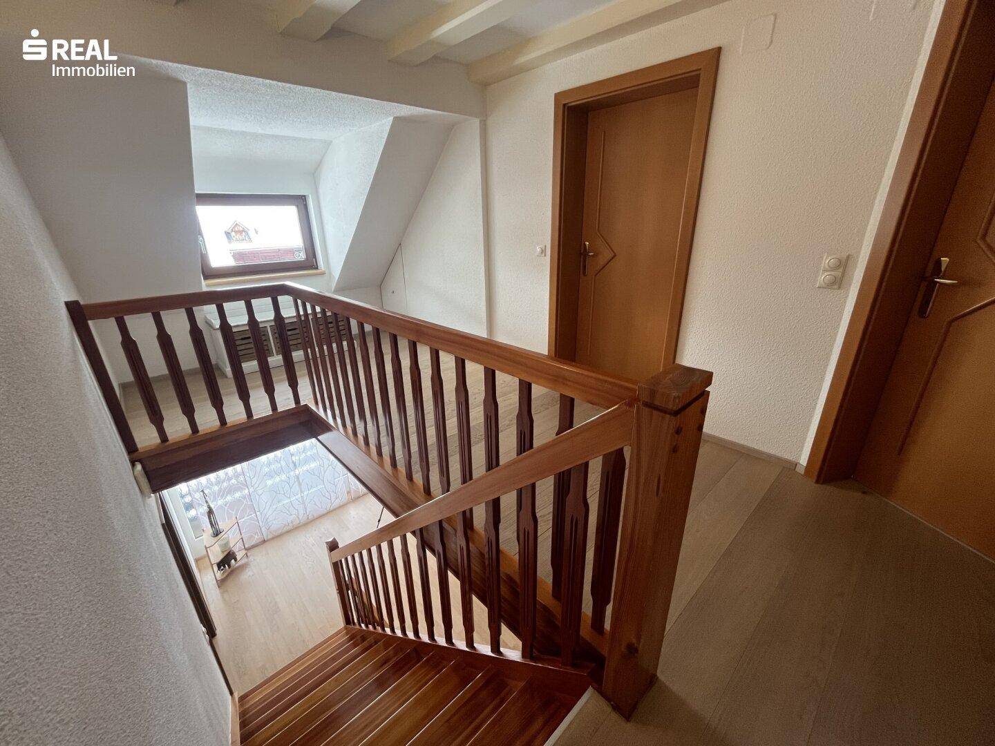 Geräumiger Flur mit Holztreppe und hellem Holzboden, der die Etagen verbindet.