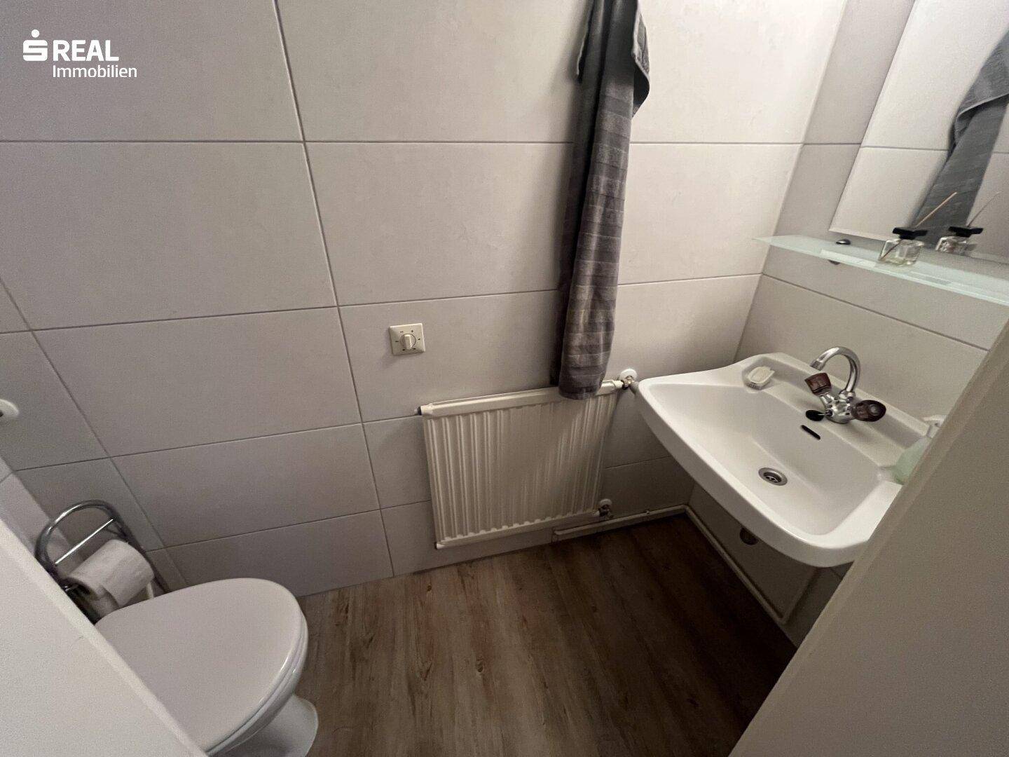 Kleines WC mit Waschbecken und Toilette, ausgestattet mit Fliesenboden.