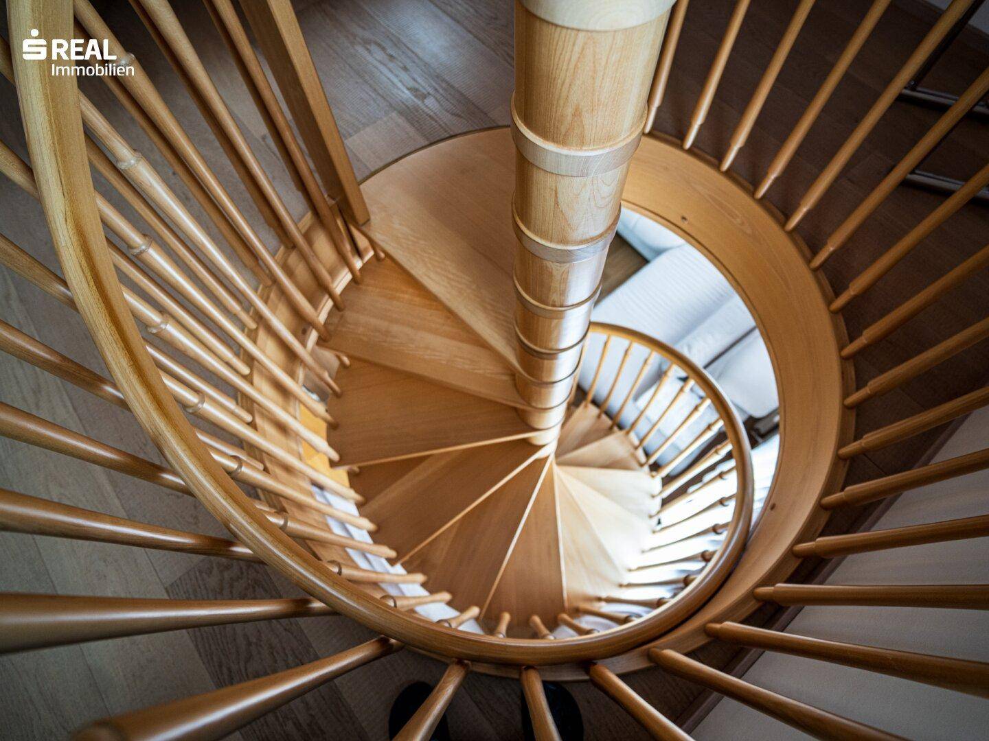 Elegante Holz-Wendeltreppe, die die verschiedenen Ebenen des Hauses miteinander verbindet.