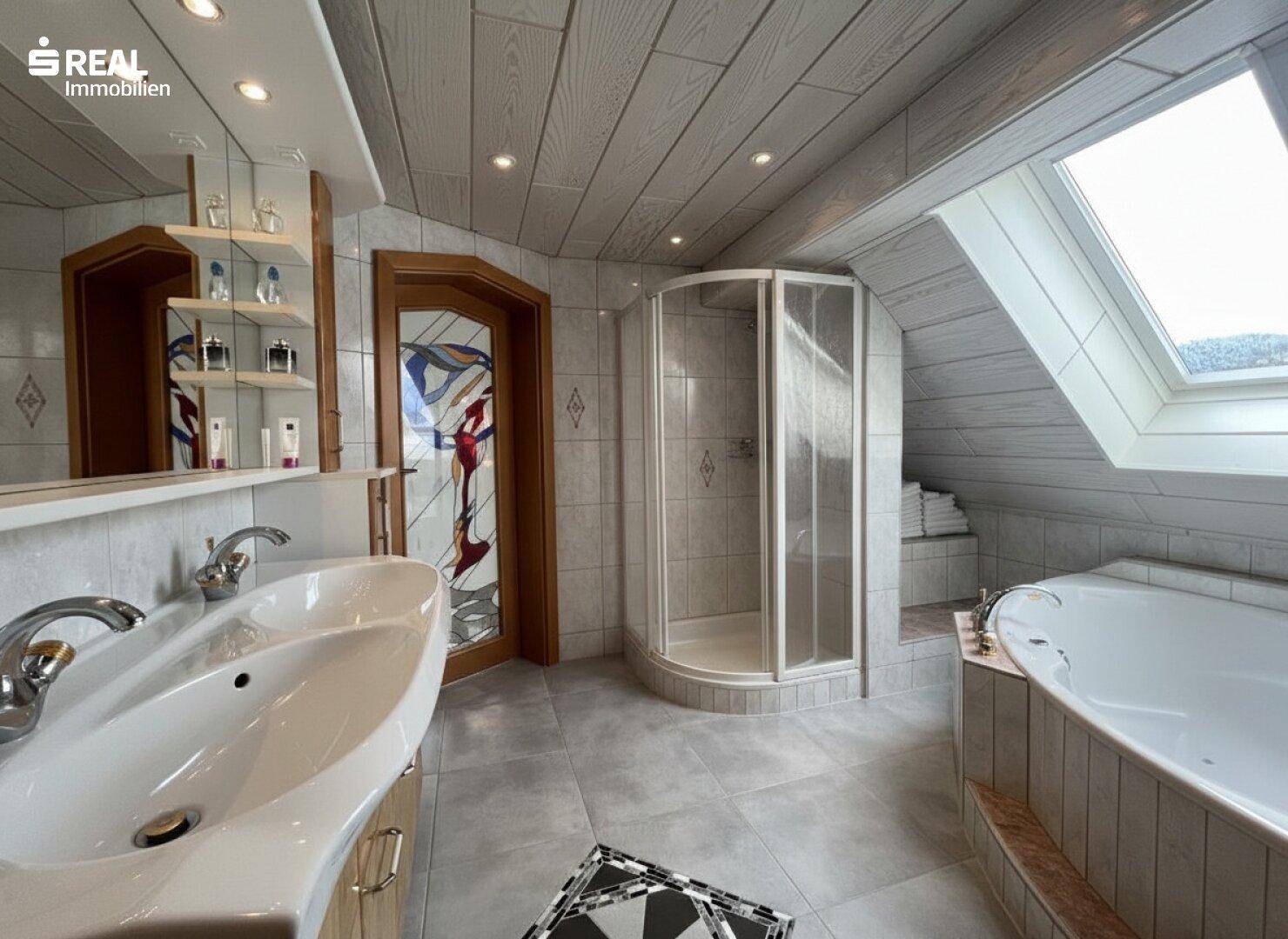 Helles Badezimmer im Dachgeschoss mit Badewanne, Dusche und Dachfenster.