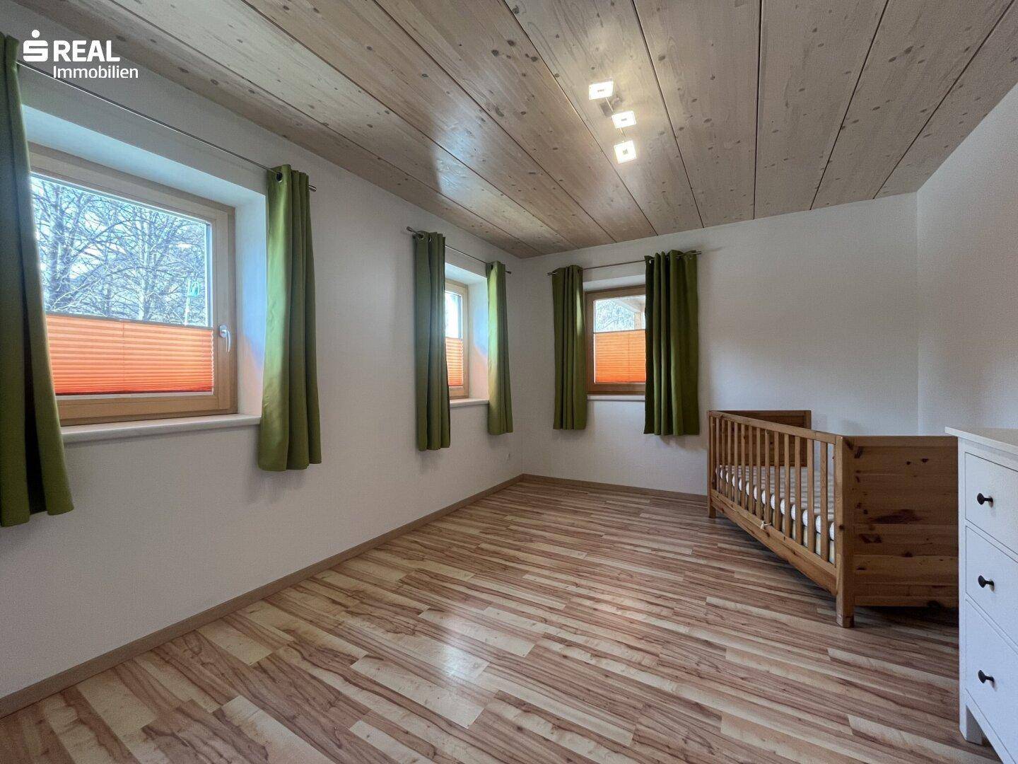 Helles Schlafzimmer oder Kinderzimmer mit Holzboden, Holzdecke und mehreren Fenstern.