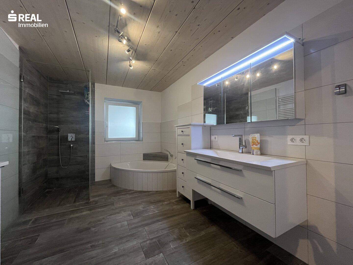 Modernes Badezimmer mit begehbarer Dusche, runder Badewanne und großem Spiegelschrank.