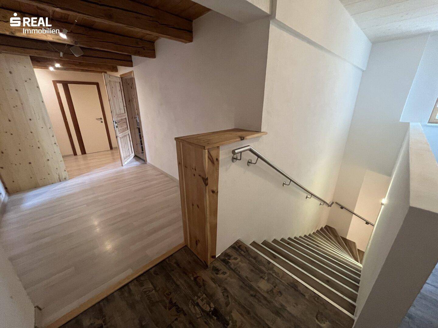 Treppenhaus mit Holzstufen und Metallgeländer, verbindet die verschiedenen Etagen des Hauses.