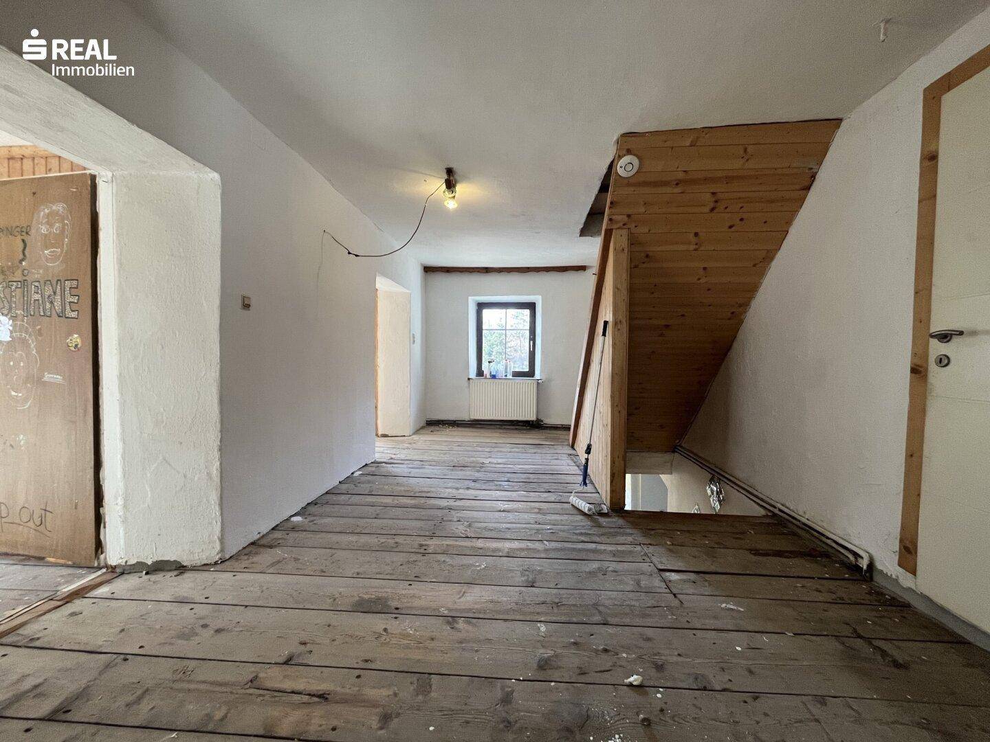 Flur mit Holzplankenboden und offener Holztreppe, die zu den oberen Etagen führt.
