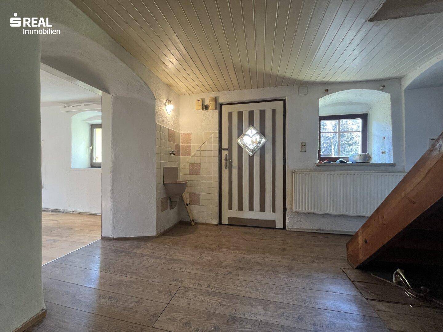 Eingangsbereich mit Holzboden und -decke, traditionellem Waschbecken und Zugang zu weiteren Räumen.