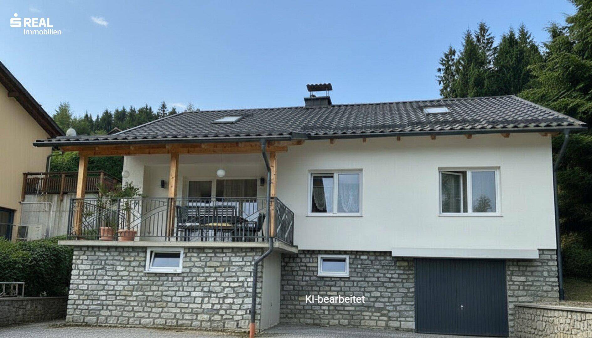 Modernes Einfamilienhaus mit weißer Fassade, Steinsockel und überdachtem Balkon mit Sitzgelegenheiten und Waldblick.