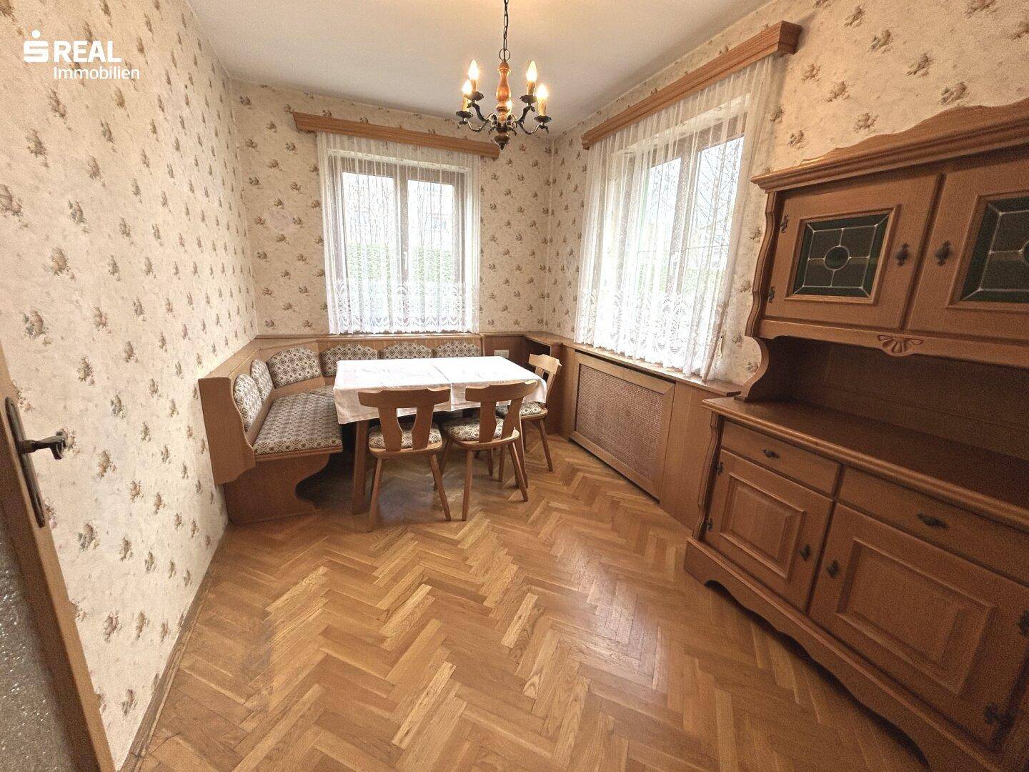 Traditioneller Essbereich mit Eckbank, Holzmöbeln und gemusterter Tapete.