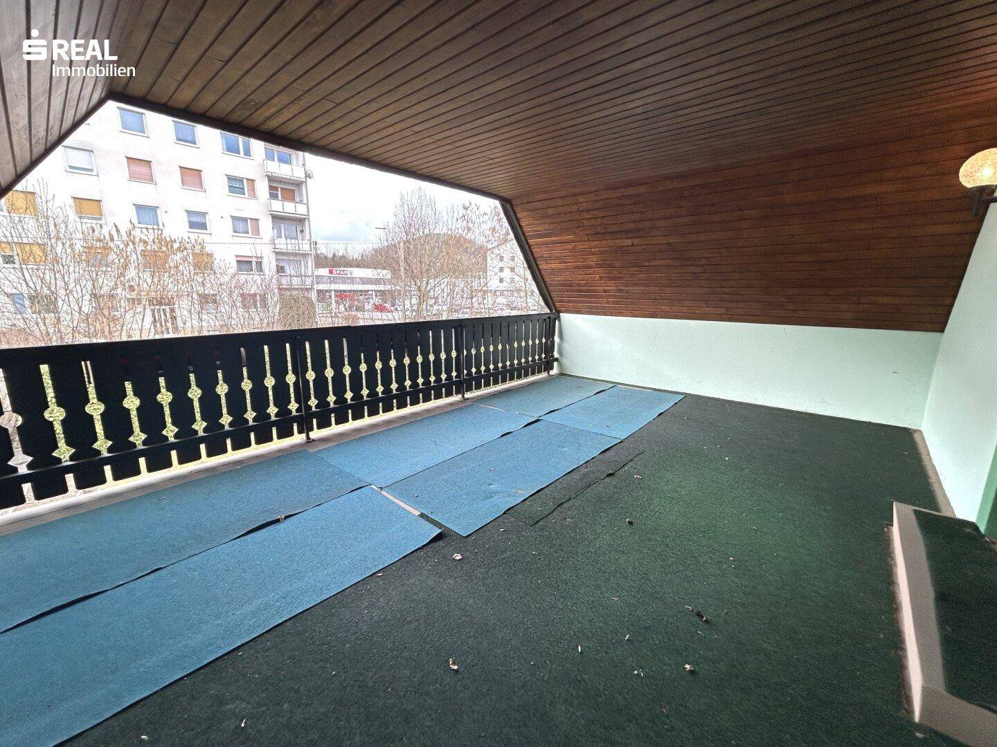 Großer Balkon mit Holzdach und weitem Blick auf die Umgebung.