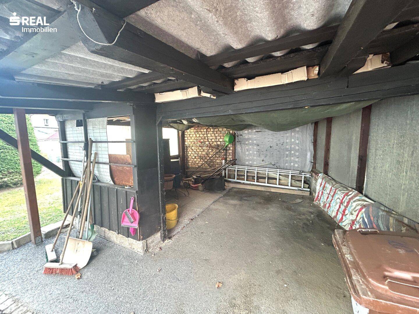 Offene Garage oder Schuppen mit Lagerfläche für Gartengeräte.