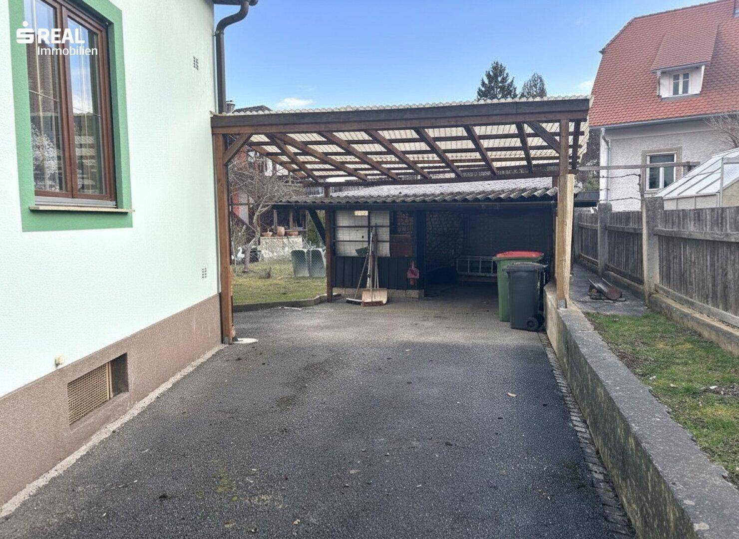 Carport-Bereich mit Abstellmöglichkeiten und Blick auf den Garten.