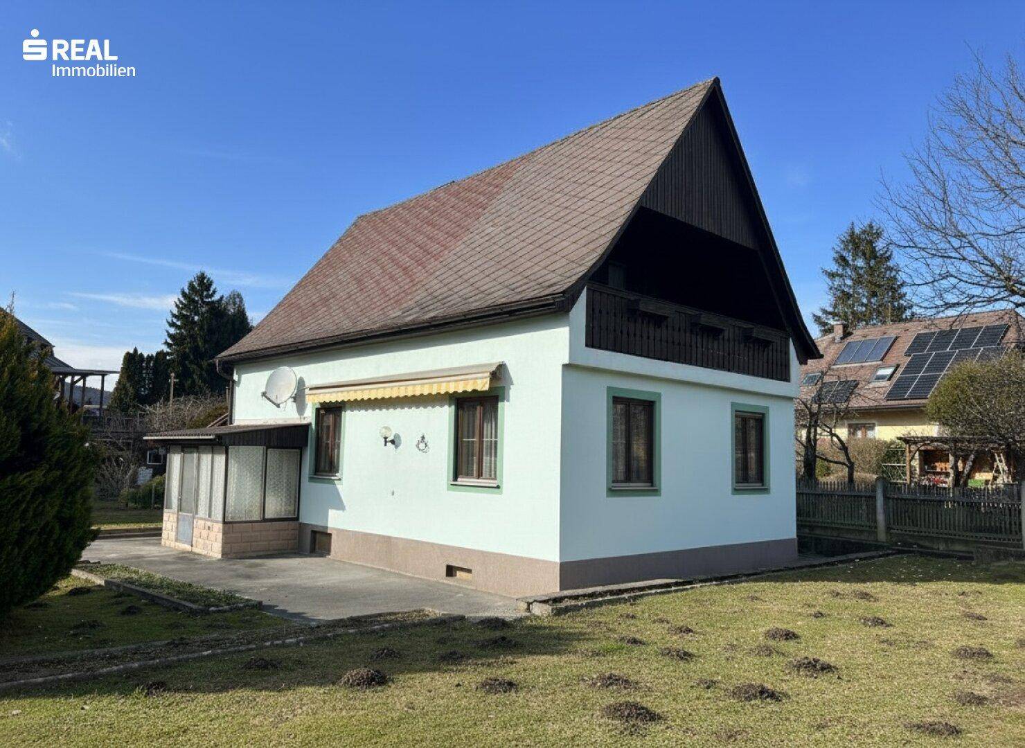 Rückansicht des Hauses mit Gartenbereich und überdachtem Eingangsbereich.